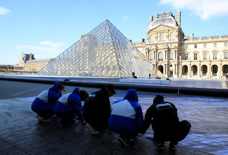 French artist JR (C) works in the courtyard of the Louvre Museum near the glass pyramid designed by Ieoh Ming Pei as the Louvre Museum celebrates the 30th anniversary of its glass pyramid in Paris, France, March 26, 2019. REUTERS/GonzaloÊFuentes