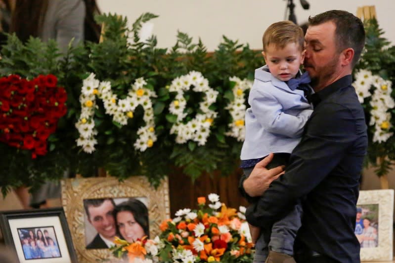 Tyler Johnson, husband of Christina Marie Langford Johnson, who was killed by unknown assailants, holds a child during her funeral service, before a burial at the cemetery in LeBaron, Chihuahua