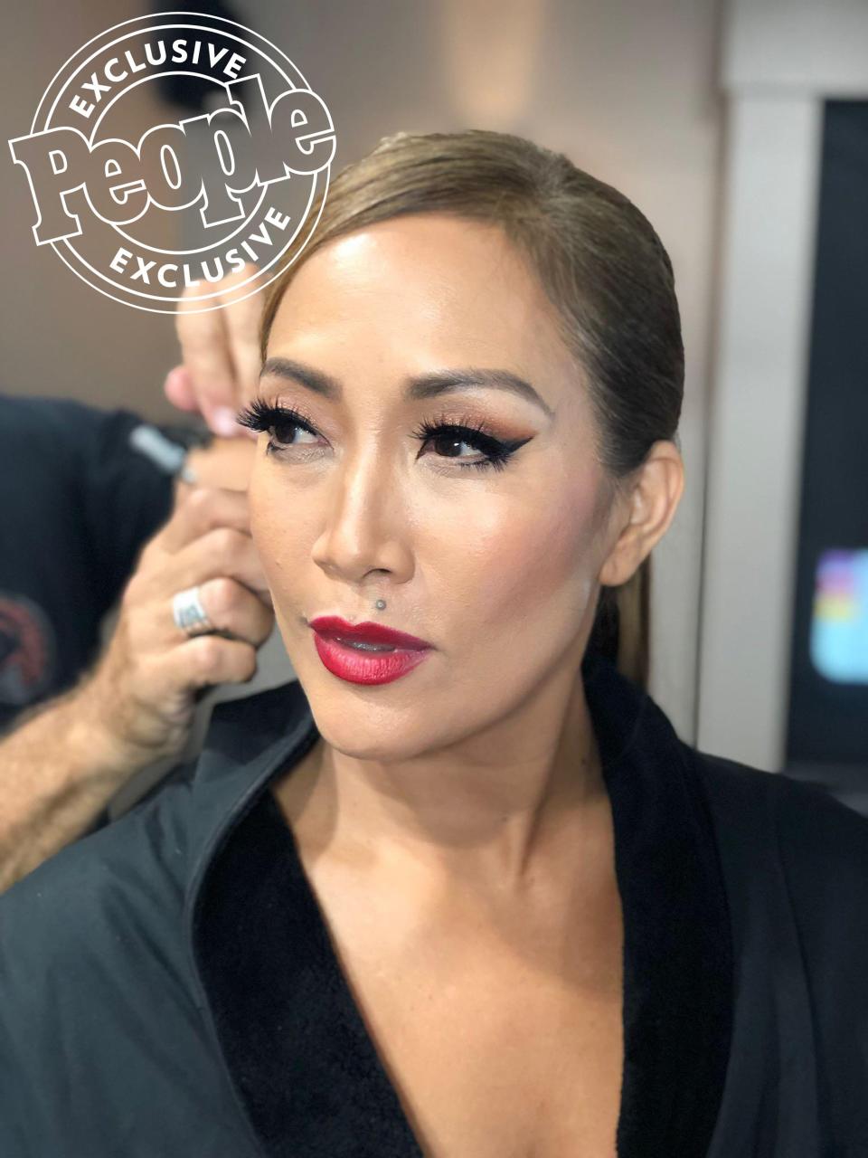 Carrie Ann’s Fouad Sarkis gown has such a stunning neckline, I had to showcase her skin,” says makeup artist Marylin Lee Spiegel. “I gave her highlights using <a href="https://click.linksynergy.com/deeplink?id=93xLBvPhAeE&mid=24449&murl=https%3A%2F%2Fwww.net-a-porter.com%2Fgb%2Fen%2Fproduct%2F1077616%2Frituel_de_fille%2Frare-light-luminizer---anthelion&u1=PEO%2CCarrieAnnInaba%27sDWTSPhotoDiary%3ASeeHowtheJudgeGetsReadyBehindtheScenes%2Channakateflanagan1%2CUnc%2CGal%2C7299401%2C201911%2CI" rel="nofollow noopener" target="_blank" data-ylk="slk:Rituel de Fille’s Rare Light Luminizer in Anthelion;elm:context_link;itc:0;sec:content-canvas" class="link ">Rituel de Fille’s Rare Light Luminizer in Anthelion</a>, a creamy, shimmery, golden cream.” 