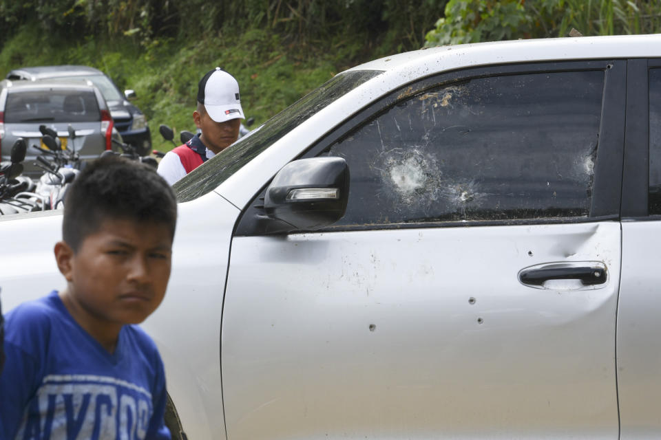 People gather around a car riddled by bullets on the road leading to Tacueyo, in southwest Colombia, Wednesday, Oct. 30, 2019. Five indigenous leaders of the Tacueyo reservation were killed late Tuesday when the two vehicles they were traveling in were ambushed by gunmen the government says are part of a dissident front of Revolutionary Armed Forces of Colombia. (AP Photo/Christian Escobar Mora)