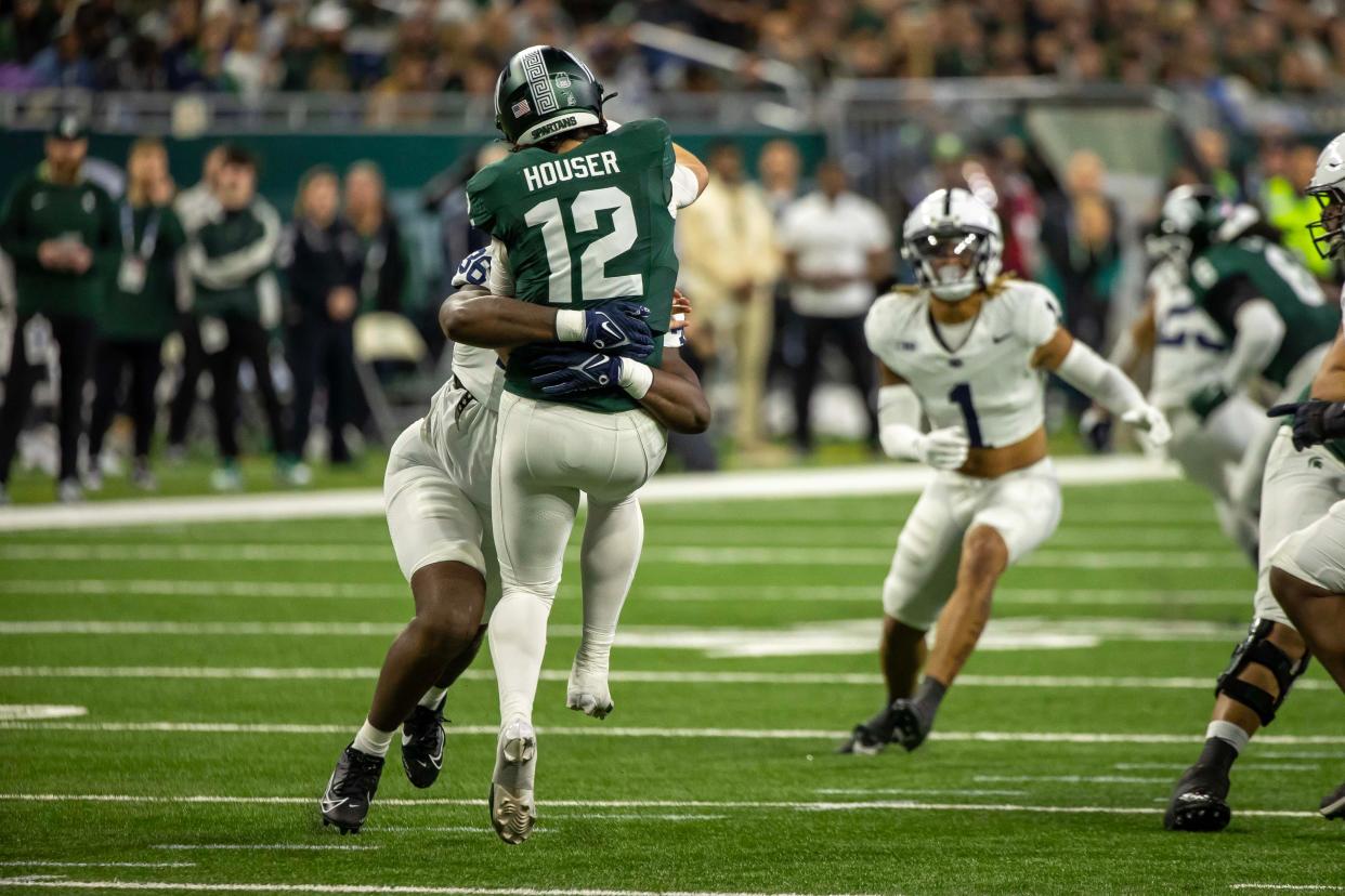 Michigan State quarterback Katin Houser passes the ball while hit by Penn State defensive end Zuriah Fisher during the first half on Friday, Nov. 24, 2023, at Ford Field.