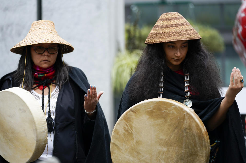 Vanessa Gloria, left, and Maggie Cooper, right, both of the Duwamish Tribe, hold out their arms during remarks from Duwamish councilwoman Desiree Fagan before a celebratory march for Indigenous Peoples Day, Monday, Oct. 9, 2023, in Seattle. (AP Photo/Lindsey Wasson)