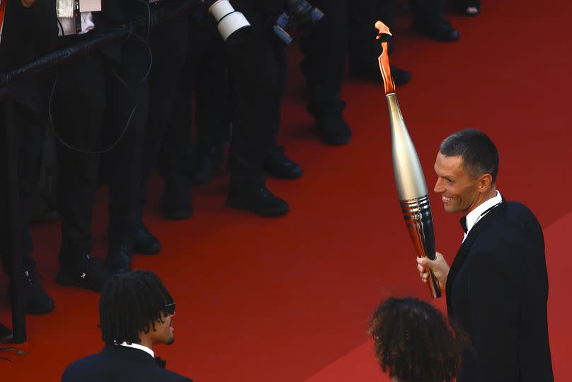 Alexis Hanquinquant (rechts) posiert für die Fotografen mit dem olympischen Feuer bei der Premiere des Films "Marcello Mio“.