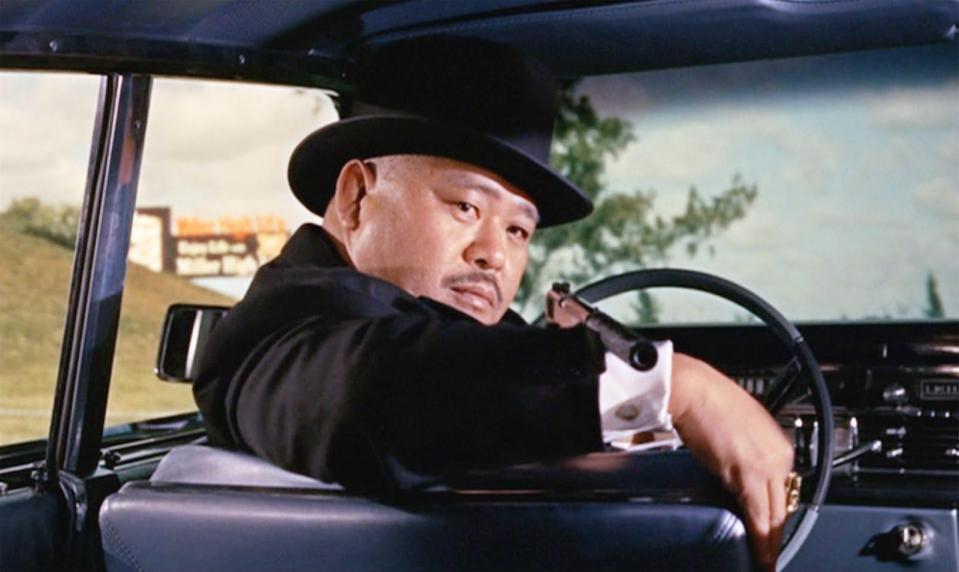 Harold Sakata pointing a gun