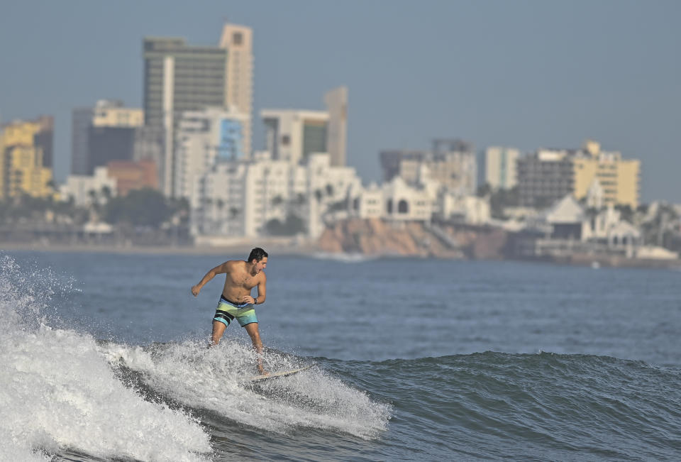 A man surfs on Pinitos beach, prior the landfall of tropical storm, Pamela, in Mazatlan, Mexico, Tuesday, Oct. 12, 2021. Hurricane Pamela weakened to a tropical storm Tuesday afternoon as it meandered off Mexico's Pacific coast. Forecasters said it was expected to regain strength overnight and be a hurricane when making landfall somewhere near the port of Mazatlan Wednesday. (AP Photo/Roberto Echeagaray)