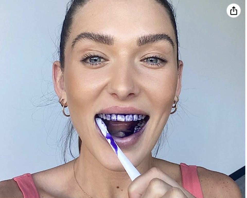 woman using purple toothpaste