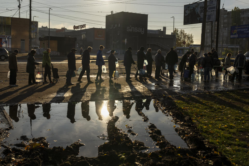 People queuing up hold plastic bottles to refill drinking water from a tank in the center of Mykolaiv, Monday, Oct. 24, 2022. Since mid-April, citizens of Mykolaiv, with a pre-war population of half a million people, have lived without a centralized drinking water supply. Russian Forces cut off the pipeline through which the city received drinking water for the last 40 years. (AP Photo/Emilio Morenatti)