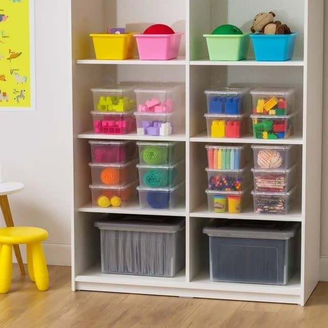 bins stacked and filled with toys, yarn, chalk, etc.