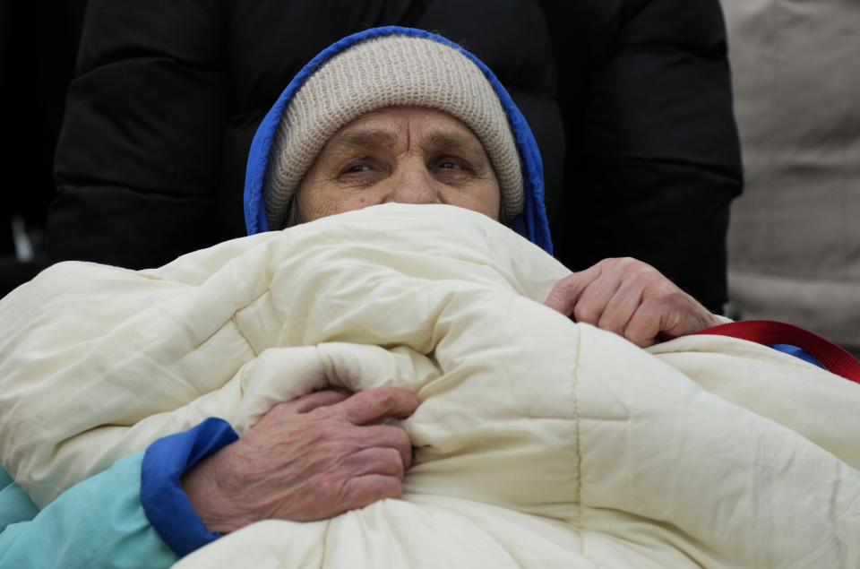 FILE A person is bundled in a blanket as people wait in a queue after fleeing the war from neighbouring Ukraine, at the border crossing in Medyka, southeastern Poland, on Tuesday, March 29, 2022. Since the invasion of Ukraine more than eight months ago, Poland has aided the neighboring country and millions of its refugees — both to ease their suffering and to help guard against the war spilling into the rest of Europe. But a missile strike that killed two men Tuesday, Nov. 15 in a Polish village close to the Ukrainian border brought the conflict home and added to the long-suppressed sense of vulnerability in a country where the ravages of World War II are well remembered. (AP Photo/Sergei Grits, File)