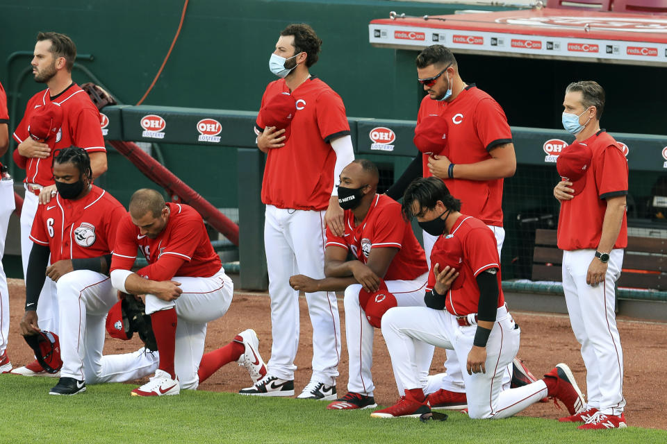 Cincinnati Reds' Phillip Ervin, left, Joey Votto, left middle, Amir Garrett, middle, and Alex Blandino, right, kneel during the national anthem prior to an exhibition baseball game against the Detroit Tigers at Great American Ballpark in Cincinnati, Tuesday, July 21, 2020. (AP Photo/Aaron Doster)