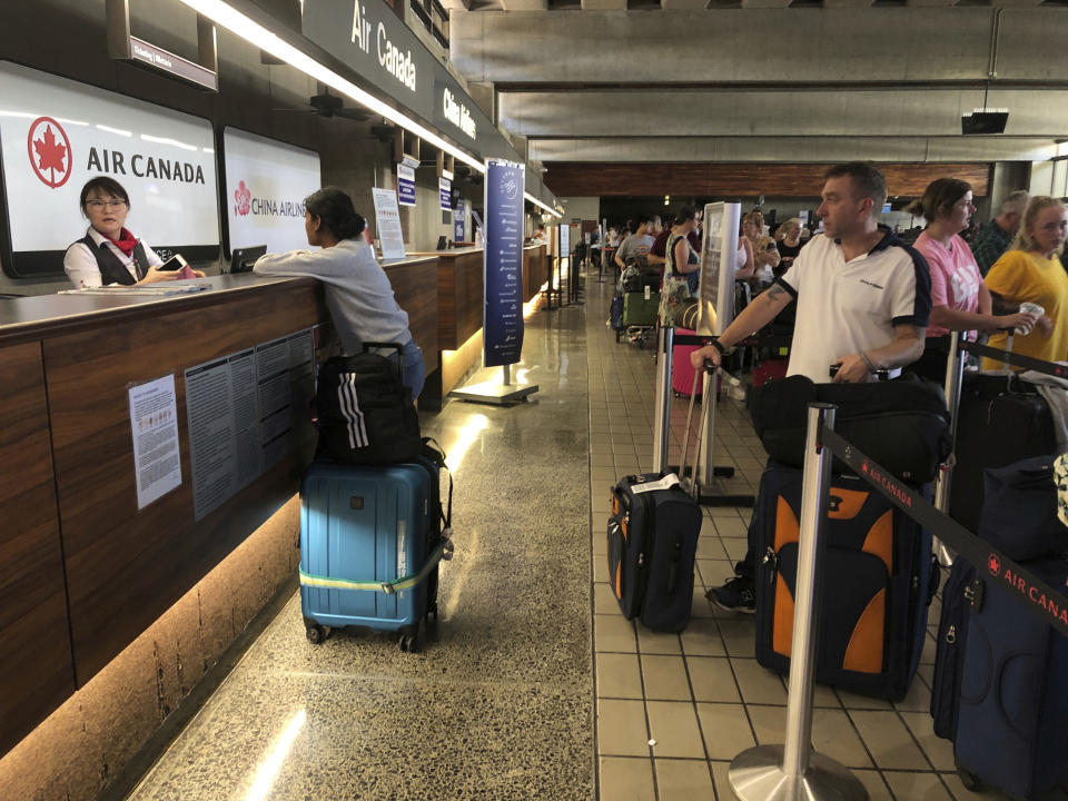 Passengers from an Australia-bound Air Canada flight diverted to Honolulu Thursday, July 11, 2019, after about 35 people were injured during turbulence, stand in line at the Air Canada counter at Daniel K. Inouye International Airport to rebook flights. Air Canada said the flight from Vancouver to Sydney encountered "un-forecasted and sudden turbulence," about two hours past Hawaii when the plane diverted to Honolulu. (AP Photo/Caleb Jones)