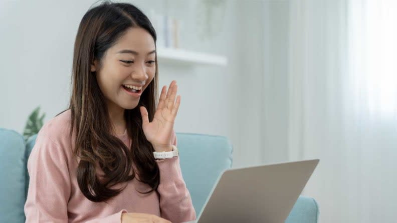 Woman shopping online with a laptop on a couch.