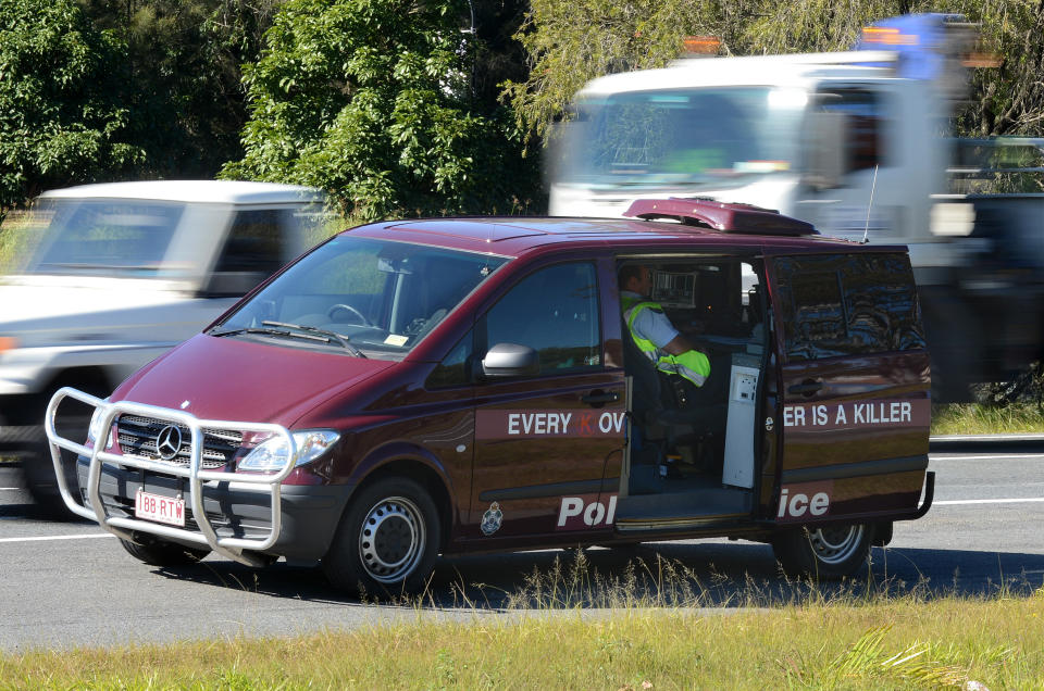 A police officer operates a mobile speed camera from the back of a van on the Pacific Highway on the Gold Coast.