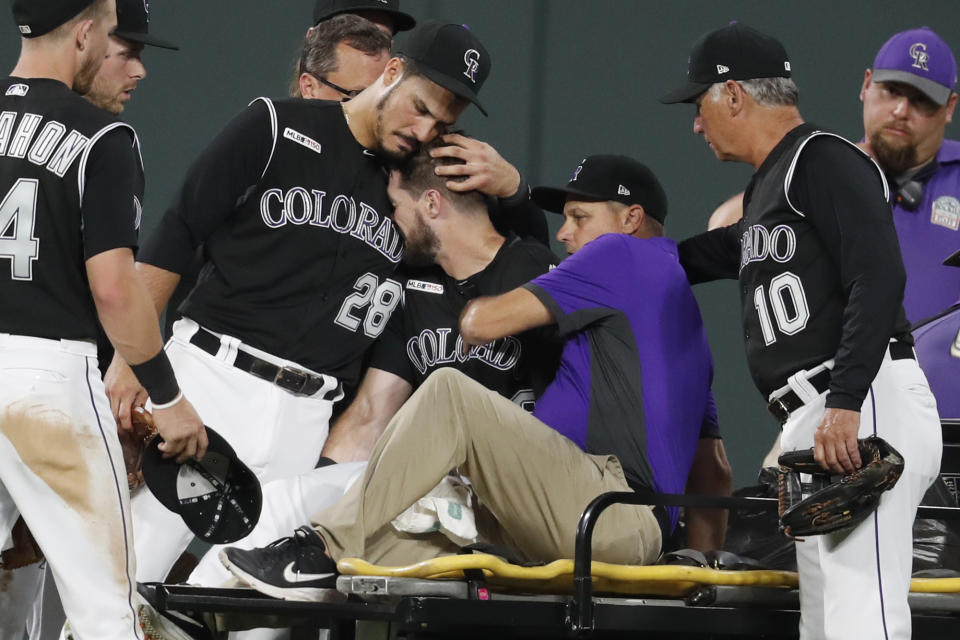 Colorado Rockies third baseman Nolan Arenado, left, consoles center fielder David Dahl, who suffered an injury to his right leg while catching a fly ball hit by San Francisco Giants' Scooter Gennett during the sixth inning of a baseball game Friday, Aug. 2, 2019, in Denver. (AP Photo/David Zalubowski)