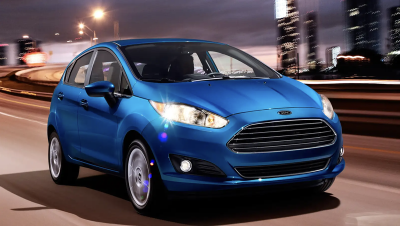 A blue Ford Fiesta driving down a city freeway