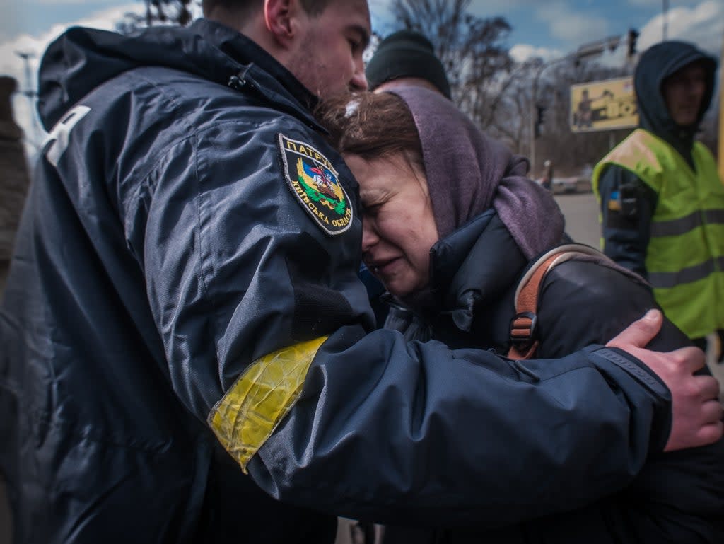 A woman from Irpin cries on a policeman’s shoulder as she is taken to an evacuation area of Kyiv (Alina Smutko)