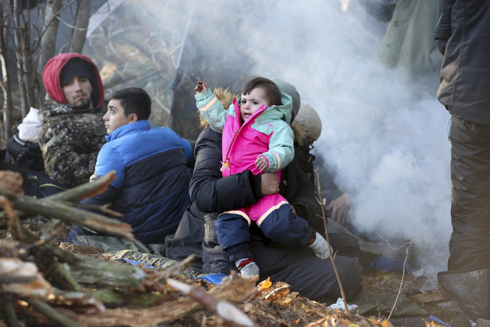 A man carries a child as he gathers with other migrants from the Middle East and elsewhere at the Belarus-Poland border near Grodno Grodno, Belarus, Tuesday, Nov. 9, 2021. Hundreds if not thousands of migrants sought to storm the border from Belarus into Poland on Monday, cutting razor wire fences and using branches to try and climb over them. The siege escalated a crisis along the European Union's eastern border that has been simmering for months. (Leonid Shcheglov/BelTA via AP)