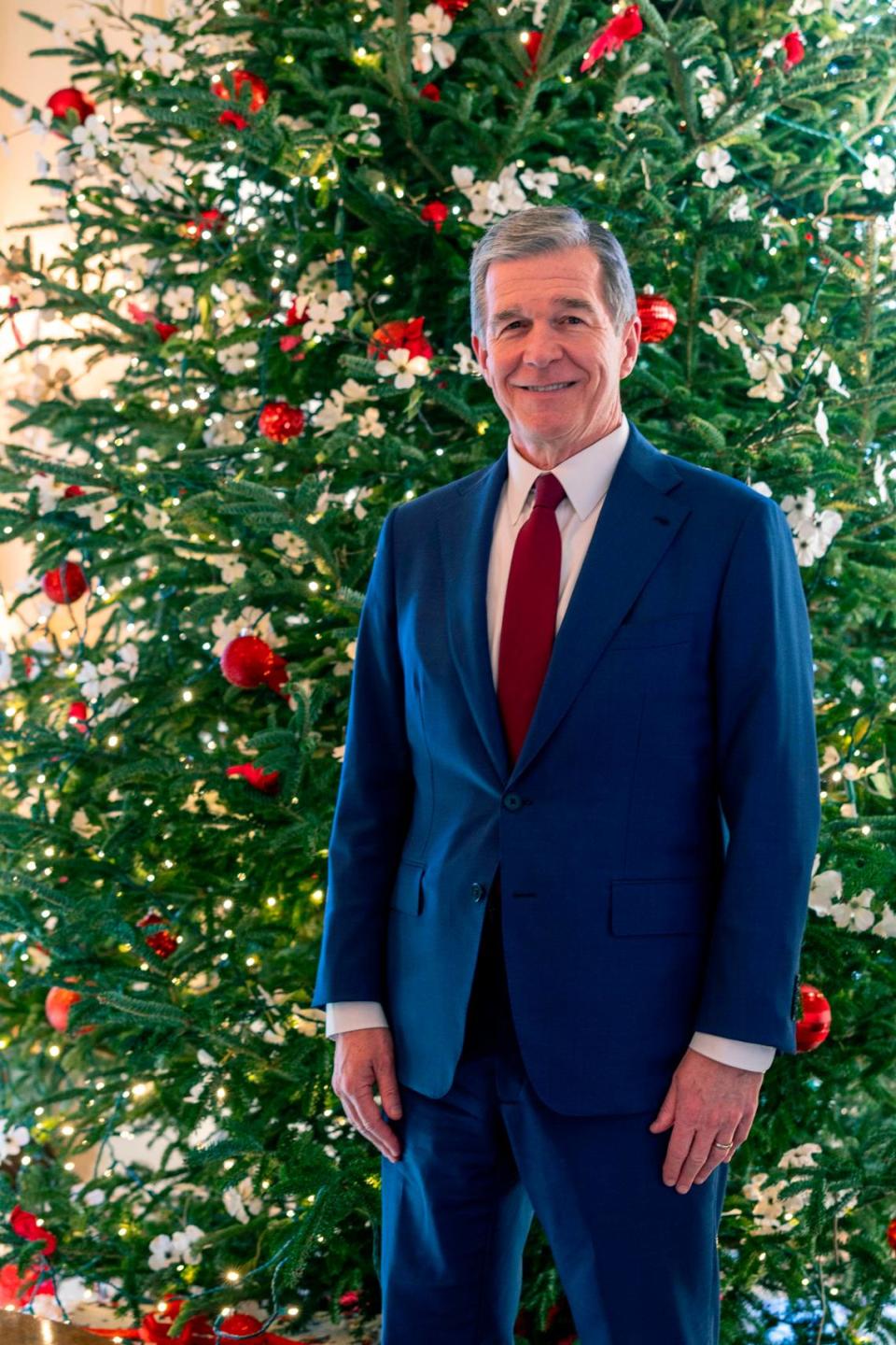 Gov. Roy Cooper stands with one of the Executive Mansion’s Christmas trees Tuesday, Dec. 9, 2023.