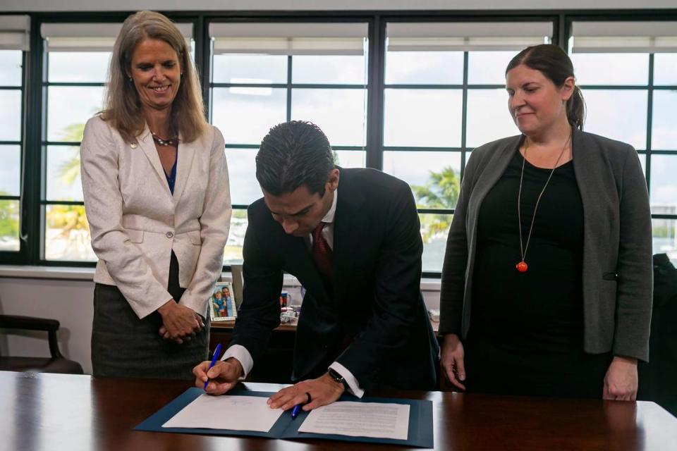 Miami Mayor Francis Suarez signs a document committing the city to carbon neutrality by 2050 at the Miami City Hall in Coconut Grove on Friday, January 17, 2019. Suarez is surrounded by Miami’s Chief Resilience Officer Jane Gilbert, left, and Laura Jay, deputy regional director for North America with C40 Cities.