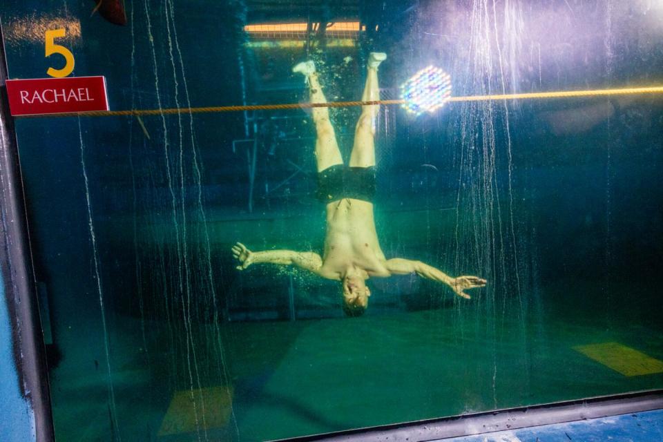 An upside-down swimmer is submerged in a water tank at Cirque du Soleil's "O."