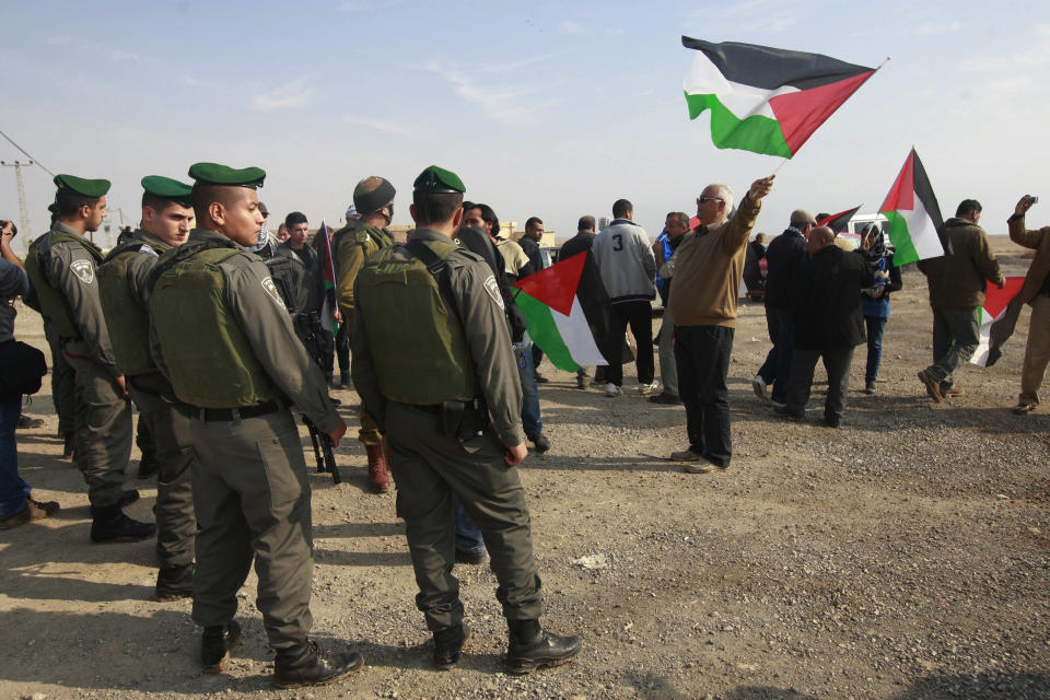 Palestinians hold national flags near Israeli border police during a demonstration over a proposed Israeli bill seeking to annex the Jordan valley, near the West Bank town of Jericho, Wednesday, Jan. 1, 2014. Israeli hard-liners, including members of Israeli Prime Minister Benjamin Netanyahu's Likud Party, have said the West Bank's Jordan Valley, a strategic area along the border with Jordan, must be annexed by Israel. The Palestinians said they couldn't establish a viable state without the valley, which makes up one-fifth of the West Bank. (AP Photo/Majdi Mohammed)