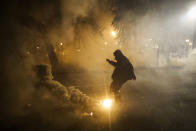 FILE - In this July 29, 2020, file photo, a demonstrator kicks a tear gas canister back at federal officers during a Black Lives Matter protest at the Mark O. Hatfield U.S. Courthouse in Portland, Ore. Night after night in Portland, tear gas and other crowd control devices enveloped protesters and bystanders in aerosolized compounds that then settled on the ground and wound up washed into storm drains. Test samples from those storm drains have turned up heavy metals and chemicals at much higher levels than samples collected from control sites elsewhere. (AP Photo/Marcio Jose Sanchez, File)