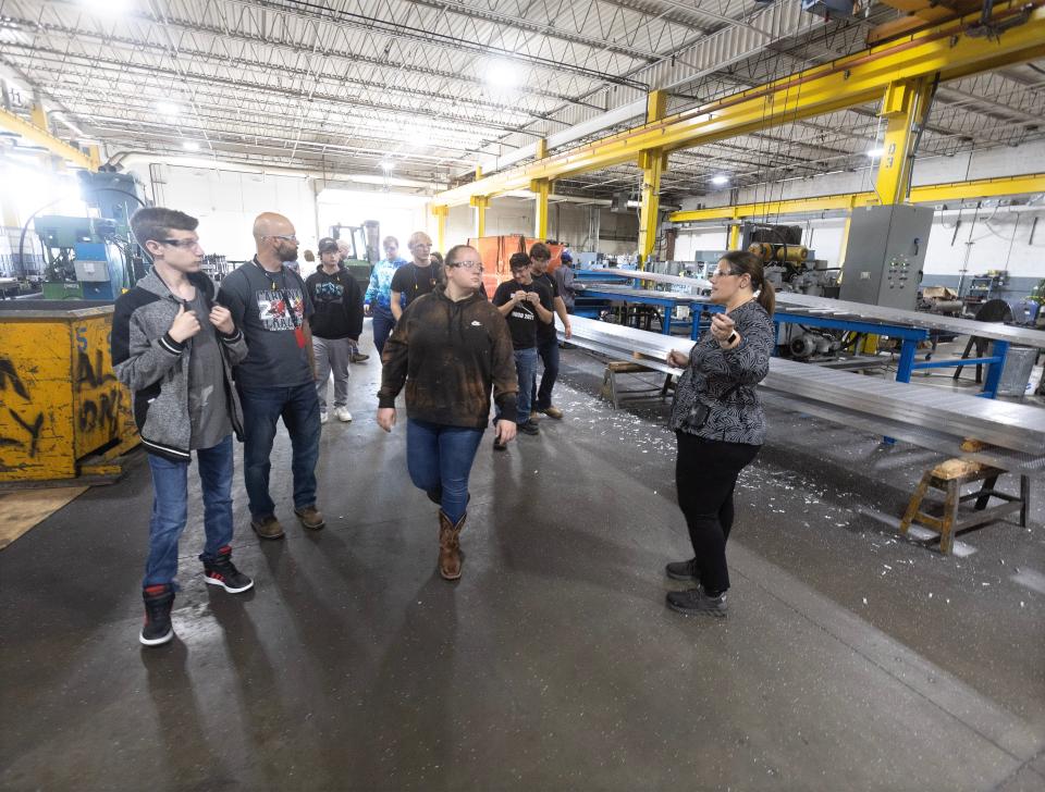 Jennifer VonWyl, materials and logistics manager at Ohio Gratings in Perry Township, leads a tour group of Sandy Valley High School students through the factory for Manufacturing Day.