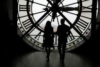 Britain's Prince William and his wife Britain's Kate look across the River Seine at a view of Paris through the clock face at the Musee d’Orsay on March 18, 2017