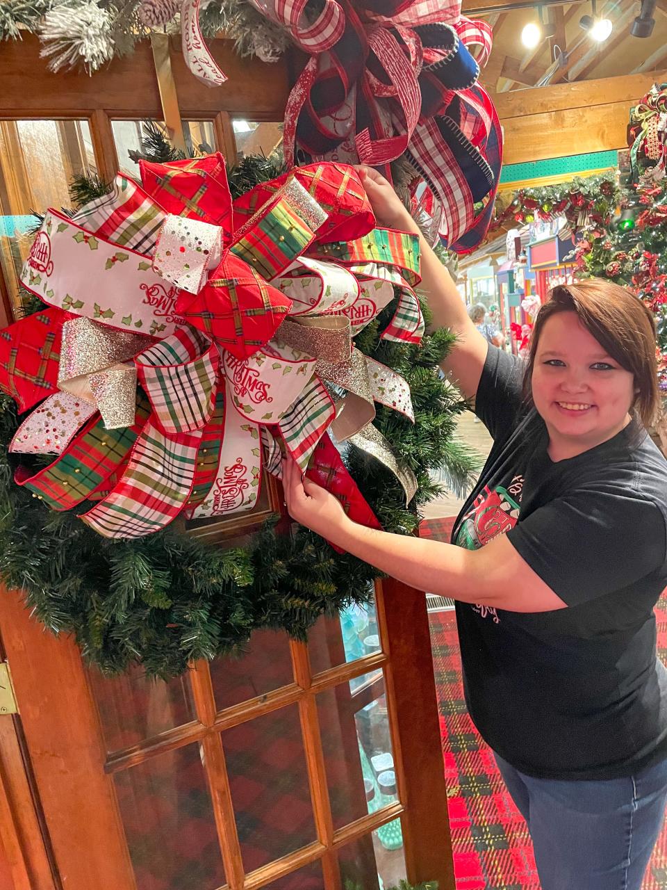 Staff member Myrissa Abernathy attaches a handmade bow to a Christmas wreath at St. Nick Nacks in Calabash.