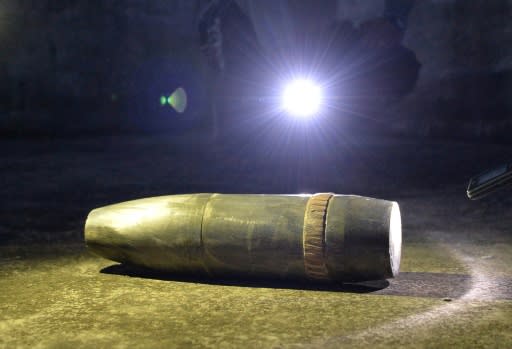 Residents use mobile lights to show what villagers says is an unexploded shell fired from Pakistan, on a rooftop of a house, at Kalal village near Nowshera in Jammu region