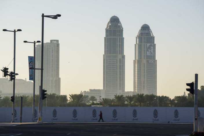 A man walks past a construction site fence in Lusail downtown, Qatar, Thursday, Nov. 24, 2022. (AP Photo/Pavel Golovkin)