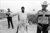 In this 1973 photo, three guards shake down and body search a prisoner and at the Cummins Unit of' Arkansas Department of Corrections in Grady, Ark. The convict-leasing period, which officially ended in 1928, helped chart the path to America's modern-day prison-industrial complex. Incarceration was used not just for punishment or rehabilitation but for profit. (Bruce Jackson via AP)
