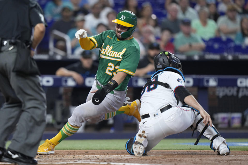 Oakland Athletics' Shea Langeliers (23) slides into home plate to score on a single by Esteury Ruiz as Miami Marlins catcher Jacob Stallings (58) waits for the throw during the third inning of a baseball game, Sunday, June 4, 2023, in Miami. (AP Photo/Wilfredo Lee)