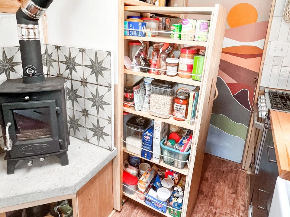 the pantry in kristin reid's converted school bus, fireplace on the left and pull-out drawer with groceries in the center