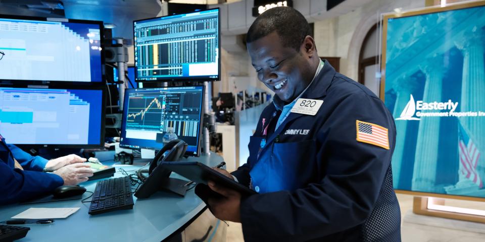 A smiling trader works on the floor of the New York Stock Exchange.