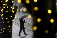 Holiday lights line trees as a pedestrian carries an umbrella while walking in the rain in San Francisco, Monday, Dec. 13, 2021. A major winter storm hitting Northern California is expected to intensify and bring travel headaches and a threat of localized flooding after an abnormally warm fall in the U.S. West. (AP Photo/Jeff Chiu)