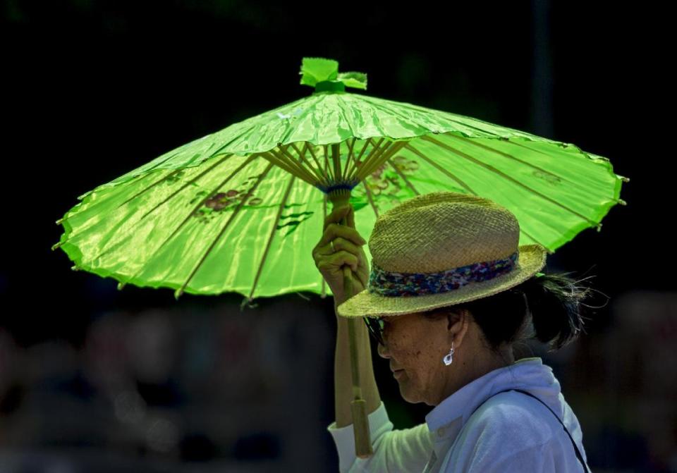 A pedestrian shields under a parasol from the hot sun in the Echo Park district in Los Angeles Wednesday, May, 14, 2014. A heat wave gripped California compounding the critical drought conditions across the state. (AP Photo)