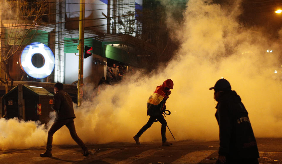 Protesters run away from tear gas fired by the police during an anti-government march against partial presidential election results in La Paz, Bolivia, late Tuesday, Oct. 22, 2019. International election monitors expressed concern over Bolivia's presidential election process Tuesday after an oddly delayed official quick count showed President Evo Morales near an outright first-round victory — even as a more formal tally tended to show him heading for a risky runoff. (AP Photo/Juan Karita)