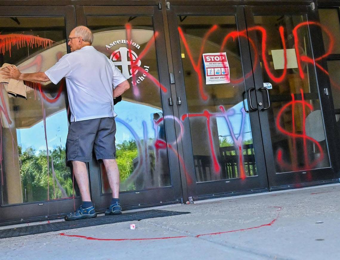 A man cleaned red paint sprayed across the entry of Ascension Catholic School in Overland Park, which is adjacent to Church of the Ascension on Sunday, July 10, 2022. The Church is at the forefront for Value Them Both campaign, which if passed on Aug. 2, would remove the right to abortion from the Kansas constitution.