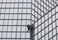 El escalador francés Alain Robert, también conocido como "hombre araña", escala el rascacielos del Tour Total en apoyo a los huelguistas de la reforma de las pensiones en el distrito financiero y de negocios de La Defense, cerca de París, Francia, el 13 de enero de 2020