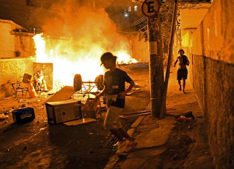 Residents run for cover during violent clashes between protestors and Brazilian Police Special Forces in a favela near Copacabana in Rio de Janeiro, Brazil on April 22, 2014