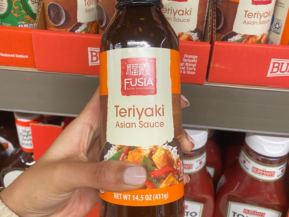 Hand holding bottle of Teriyaki sauce at Aldi