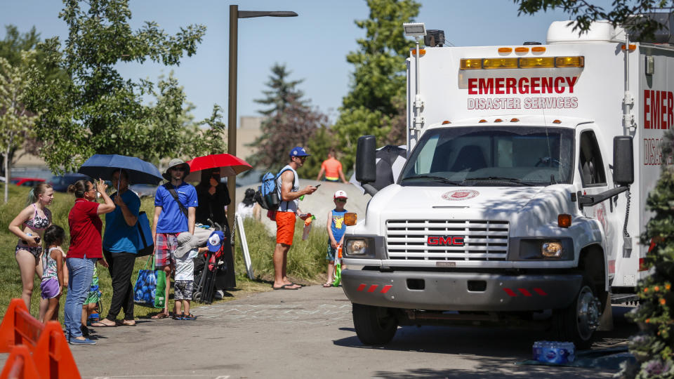 CORRECTS DATE TO WEDNESDAY, JUNE 30, 2021, INSTEAD OF TUESDAY, JUNE 29 FOR PHOTOS: JMC101-111, 113 A Salvation Army EMS vehicle is setup as a cooling station as people lineup to get into a splash park while trying to beat the heat in Calgary, Alberta., Wednesday, June 30, 2021. Environment Canada warns the torrid heat wave that has settled over much of Western Canada won't lift for days. (Jeff McIntosh/The Canadian Press via AP)