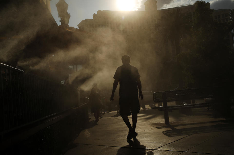 A man cools off in a water mist along the Las Vegas Strip, Thursday, July 26, 2018, in Las Vegas. The Las Vegas valley is in it's third day of a an excessive heat warning issued by the National Weather Service. (AP Photo/John Locher)