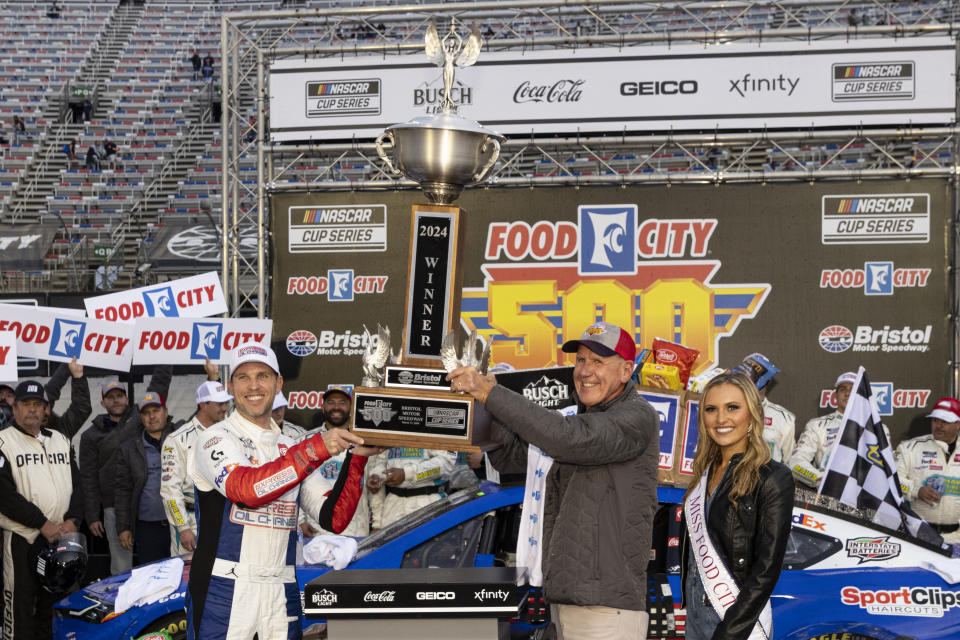 Denny Hamlin, left, hoists the trophy with Food City president Steve Smith after winning a NASCAR Cup Series auto race, Sunday, March 17, 2024, in Bristol, Tenn. (AP Photo/Wade Payne)