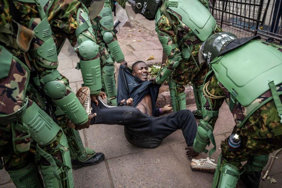 A man, wearing black, reacts on the floor as Kenya Police officers, wearing riot uniforms, arrest him while stopping people from gathering for a planned demonstration in downtown Nairobi, on June 27, 2024.