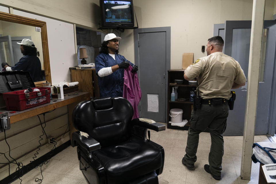 Gerald Massey, an incarcerated student majoring communications through the Transforming Outcomes Project at Sacramento State (TOPSS), talks with officer Chris Solorzano after giving him a haircut at Folsom State Prison in Re, Calif., Thursday, May 4, 2023. Prison forced Massey to take responsibility for his actions. He got focused, sought rehabilitation for alcoholism and restarted his pursuit of education. He also took up prison barbering to make money. (AP Photo/Jae C. Hong)