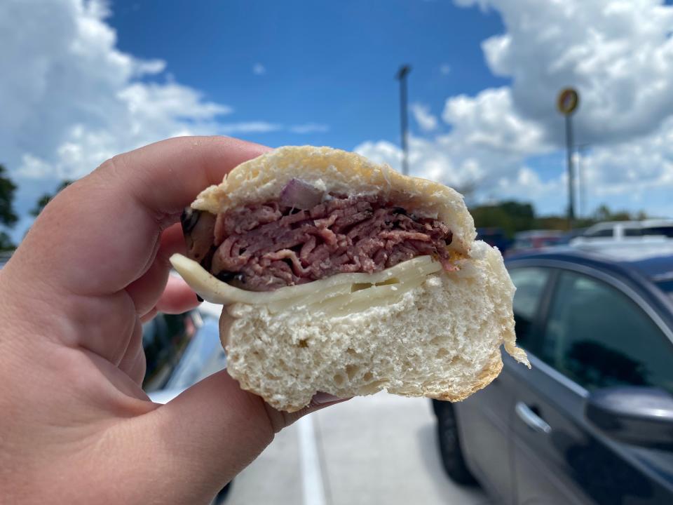 The writer holds a sandwich at Buc-ee's with a thick layer of meat and cheese