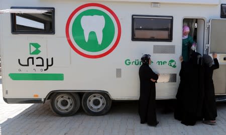 Displaced Syrian refugee women wait for their turn to get dental care at a mobile clinic near Azaz