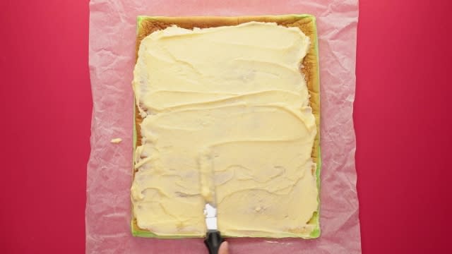 Spreading frosting over swiss roll cake